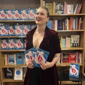 Photo of person standing in front of bookshelves holding a book